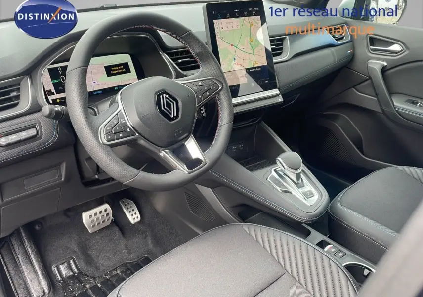 Intérieur avant du Renault Captur E-Tech hybride 2025, volant multifonction et écran tactile central visible.