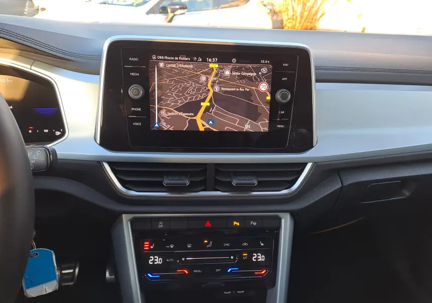 Vue frontale du tableau de bord gris clair du Volkswagen T-Roc 2025 avec écran tactile de navigation et commandes climatiques digitales.