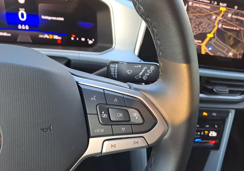 Vue rapprochée du volant noir du Volkswagen T-Roc gris Ascot 2025, avec commandes multifonctions et tableau de bord numérique.