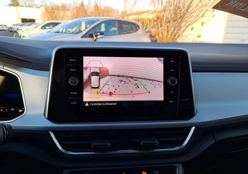 Vue intérieure du tableau de bord du Volkswagen T-Roc gris Ascot, écran central affichant la caméra de recul en action.