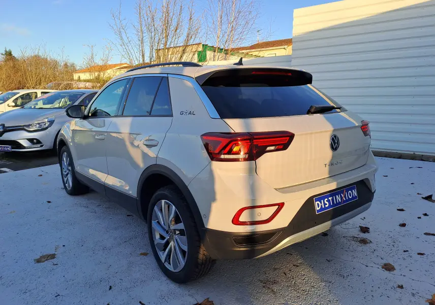 Vue 3/4 arrière droite d'un Volkswagen T-Roc gris Ascot avec vitres teintées et jantes alliage, stationné en extérieur.