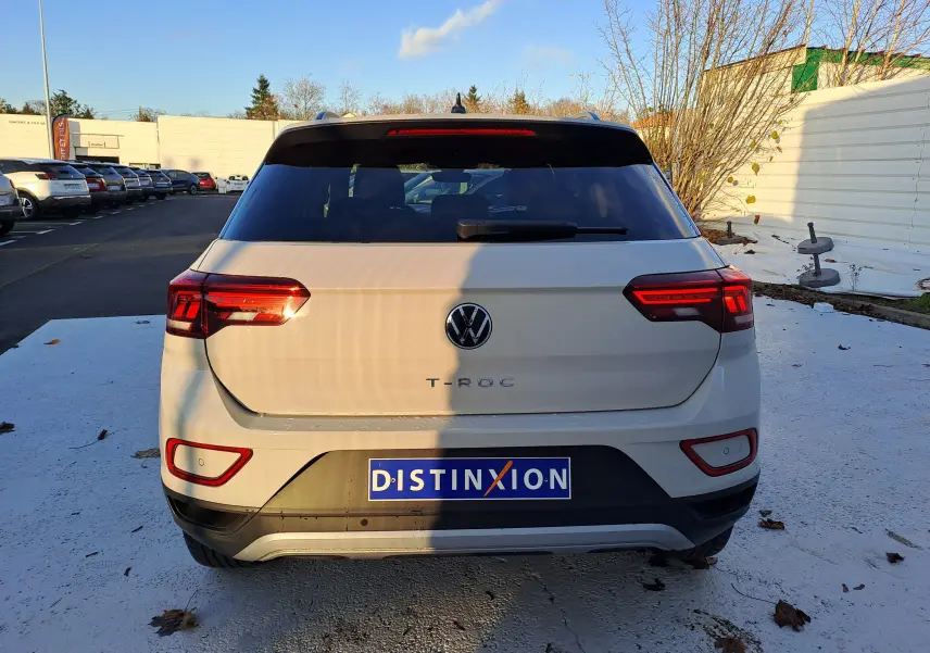 Vue arrière d'un Volkswagen T-Roc gris Ascot 2025 avec feux LED et logo distinctif sur parking.