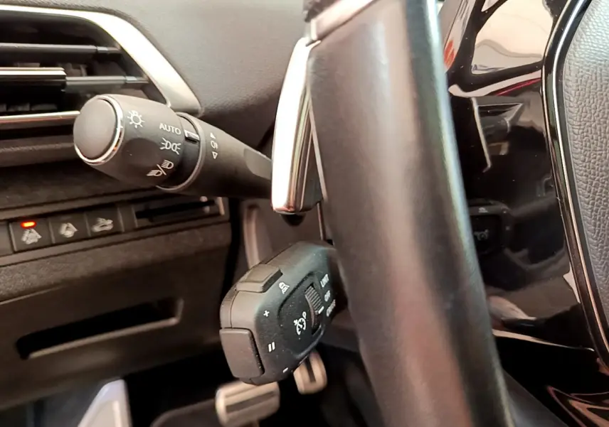 Gros plan sur la commande de régulateur et les commandes d'éclairage à gauche du volant cuir du Peugeot 3008 GT rouge 2021.