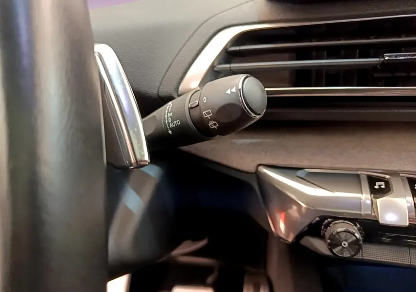 Gros plan sur la commande d’essuie-glace à gauche du volant dans l’habitacle noir du Peugeot 3008 GT rouge 2021.