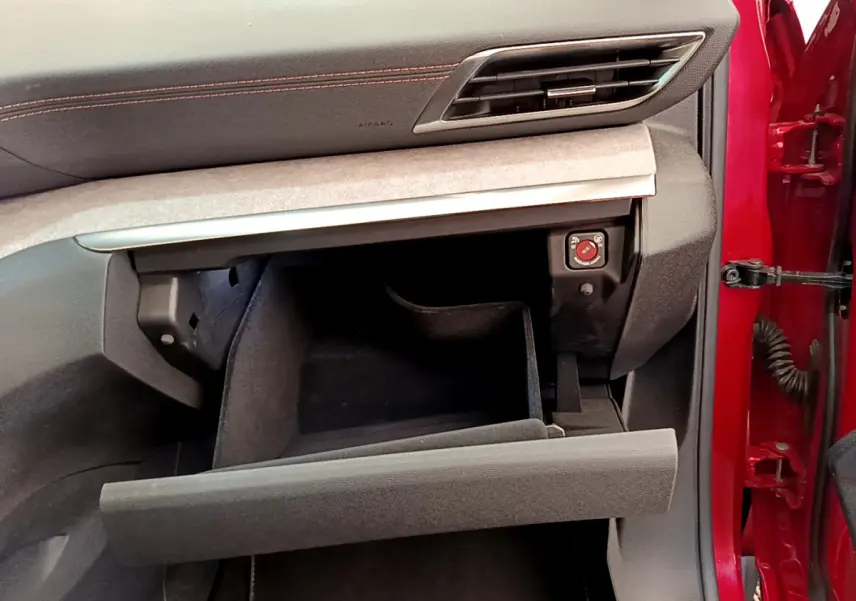 Intérieur Peugeot 3008 GT 2021 rouge, vue côté passager sur boîte à gants ouverte et tableau de bord noir avec surpiqûres rouges.