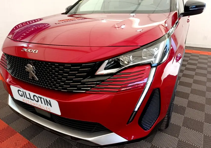 Vue 3/4 avant droit d'un Peugeot 3008 rouge avec calandre noire et feux LED distinctifs en griffes.