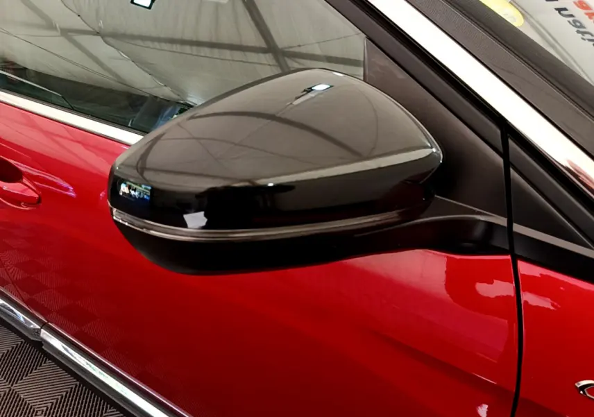 Gros plan sur le rétroviseur noir côté gauche du Peugeot 3008 GT rouge, mettant en valeur son design lisse et brillant.