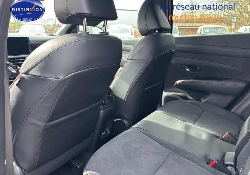 Vue intérieure arrière côté droit du Hyundai Tucson 2026, sièges en cuir noir avec surpiqûres rouges et garnitures modernes.