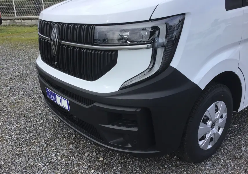 Gros plan 3/4 avant droit du Renault Master blanc, mettant en valeur la calandre noire et le phare moderne.