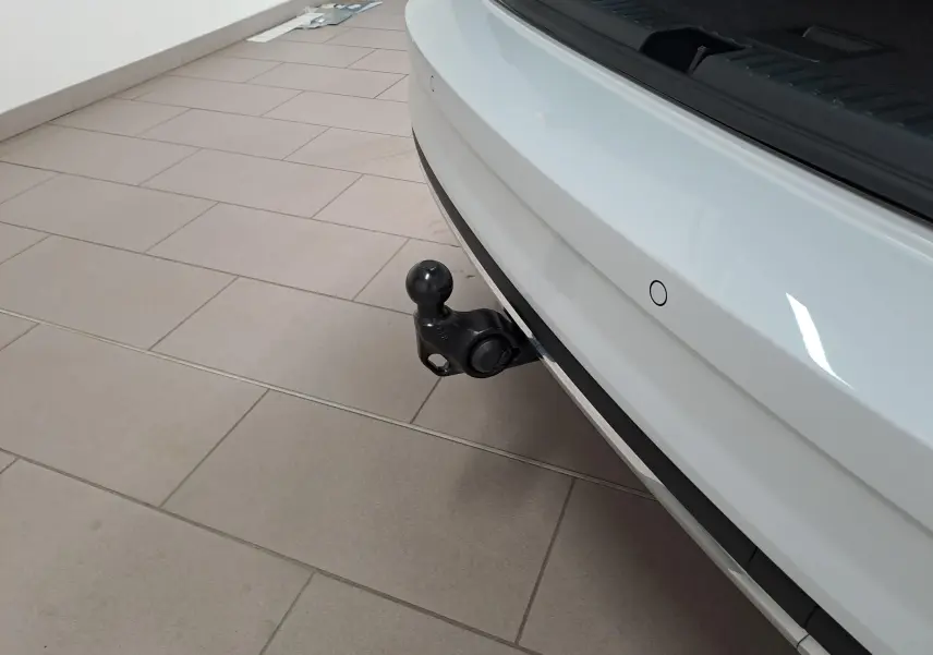 Gros plan sur l'attelage arrière noir du Skoda Karoq blanc lune 2025, avec capteur de recul visible sur le pare-chocs.