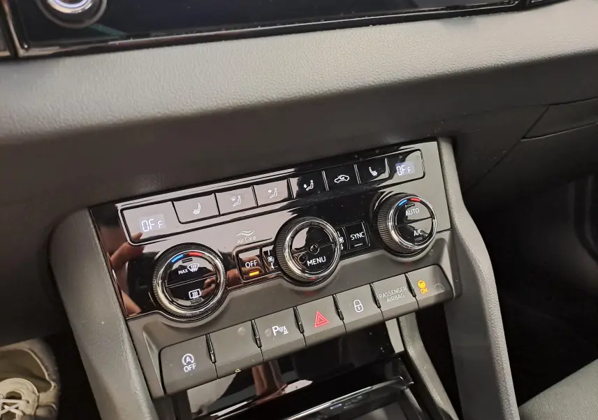 Détail de la console centrale noire du Skoda Karoq 1.5 TSI 150 DSG7 Sportline 2025, avec commandes climatisation et sièges chauffants.