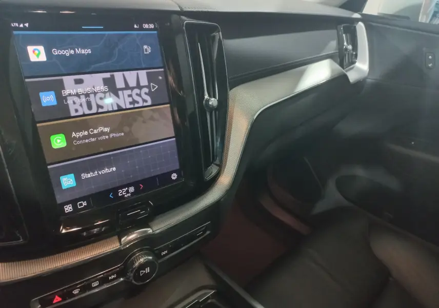 Vue intérieure côté passager du tableau de bord noir et écran tactile affichant Google Maps dans un Volvo XC60 gris clair.