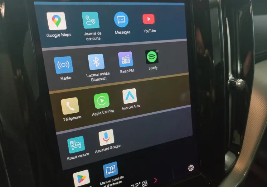 Écran tactile central du tableau de bord du Volvo XC60 gris clair, affichant les applications multimédia et connectivité.