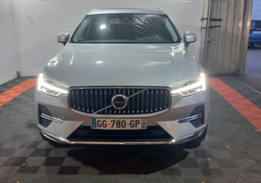 Vue frontale d'un Volvo XC60 gris clair avec phares LED allumés et calandre verticale distinctive.
