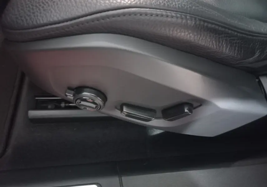 Gros plan sur les commandes de réglage électrique du siège conducteur en cuir noir du Volvo XC60 gris clair.