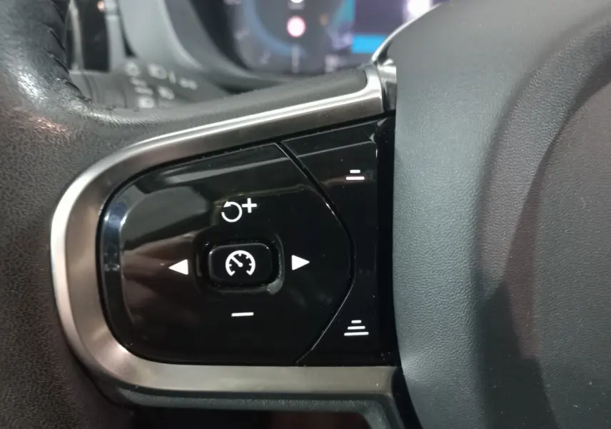 Gros plan sur les commandes de régulateur de vitesse au volant noir du Volvo XC60 gris clair B4 197 Geartronic 2022.