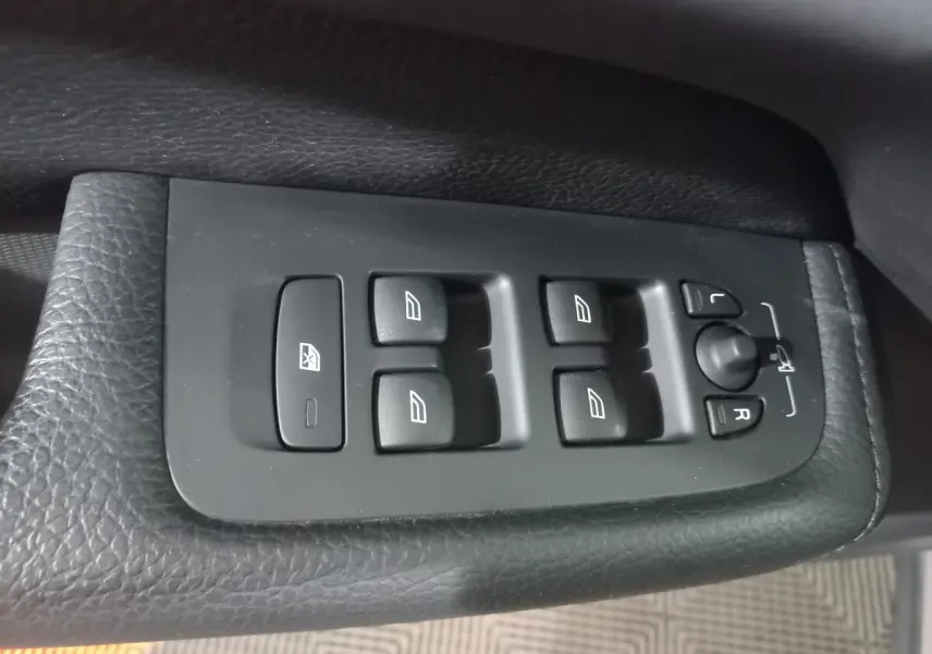Boutons de commande des vitres et rétroviseurs sur la portière côté conducteur du Volvo XC60 gris clair 2022.