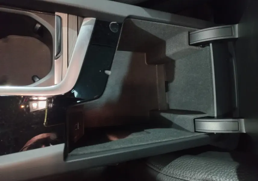 Vue rapprochée de la console centrale noire ouverte du Volvo XC60 B4 197 Geartronic 8 Inscription, intérieur gris.