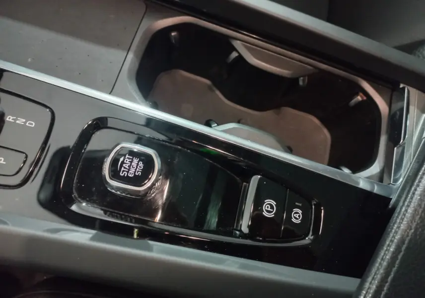 Gros plan sur la console centrale noire du Volvo XC60 B4 2022, montrant le bouton start/stop et commandes de frein à main électrique.