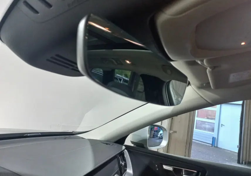 Intérieur du Volvo XC60 B4 2022, vue côté conducteur sur tableau de bord et rétroviseur gris clair.