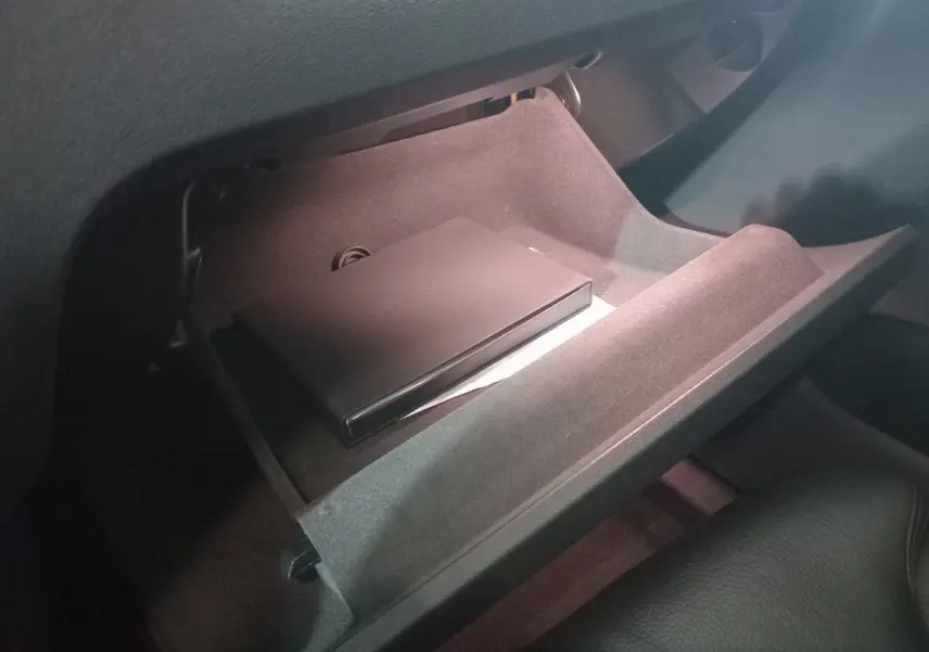 Gant de boîte ouvert côté passager du Volvo XC60 gris clair, montrant un boîtier noir à l'intérieur.