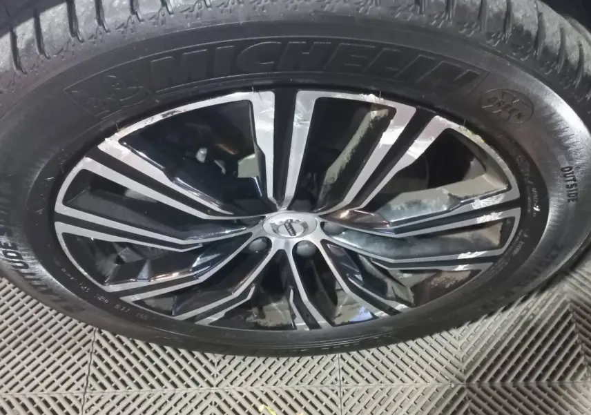 Gros plan sur la jante noire et argentée d'un Volvo XC60 gris clair avec pneu Michelin visible.