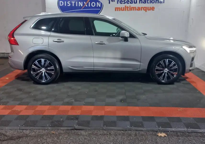Profil droit d'un Volvo XC60 gris clair 2022 garé en intérieur avec jantes alliage et feux arrière distinctifs en L.