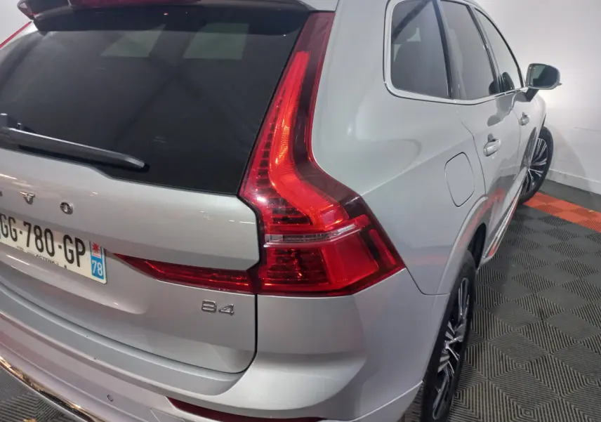 Vue 3/4 arrière droit d'un Volvo XC60 B4 gris clair avec feux arrière LED et jantes alliage noires.