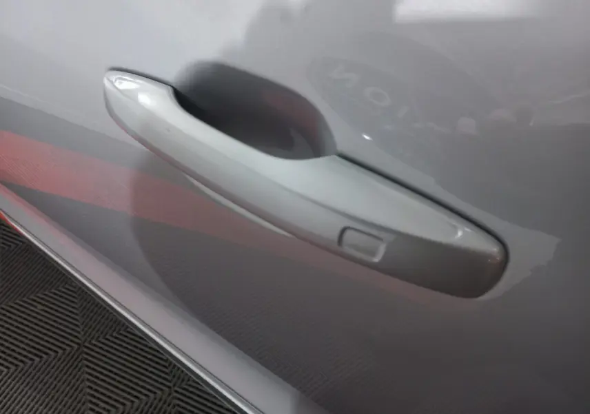 Poignée de porte gris clair en gros plan sur le côté droit d'un Volvo XC60 B4 2022 hybride essence.