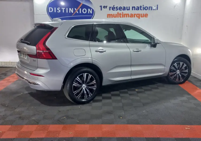 Vue côté gauche d'un Volvo XC60 gris clair B4 197 Geartronic 8 Inscription avec jantes noires et chrome en intérieur fermé.