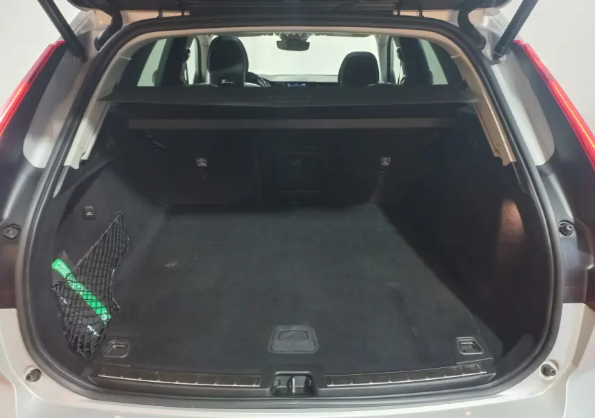 Coffre ouvert vu de l'arrière d'un Volvo XC60 gris clair, avec filet de sécurité et banquette arrière visible.