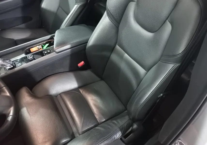 Gros plan sur le siège conducteur en cuir noir et la console centrale du Volvo XC60 B4 gris clair, intérieur soigné.