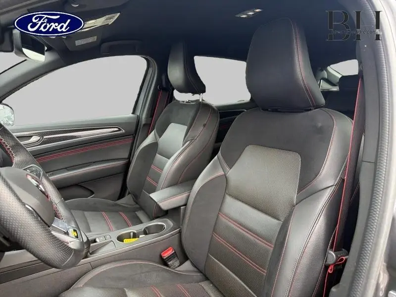 Vue intérieure avant du Renault Arkana 2023, sièges mixte cuir-suédine noir avec surpiqûres rouges et accoudoir central.