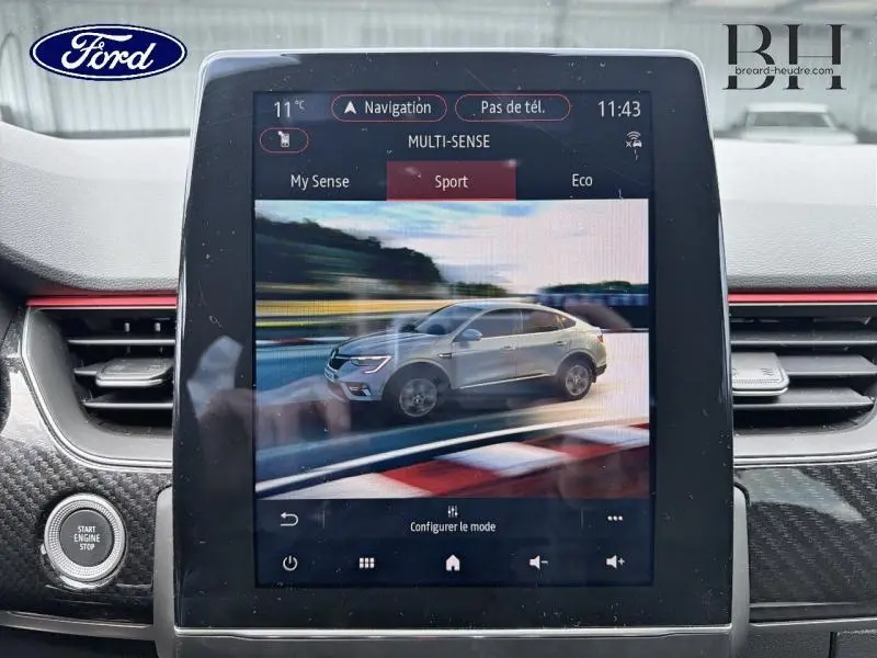 Écran tactile central montrant un Renault Arkana gris métallisé en vue latérale droite dans le mode Sport.