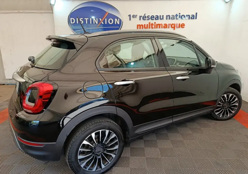 Vue 3/4 arrière droite d'un FIAT 500X noir avec jantes alliage et feux arrière LED dans un showroom.
