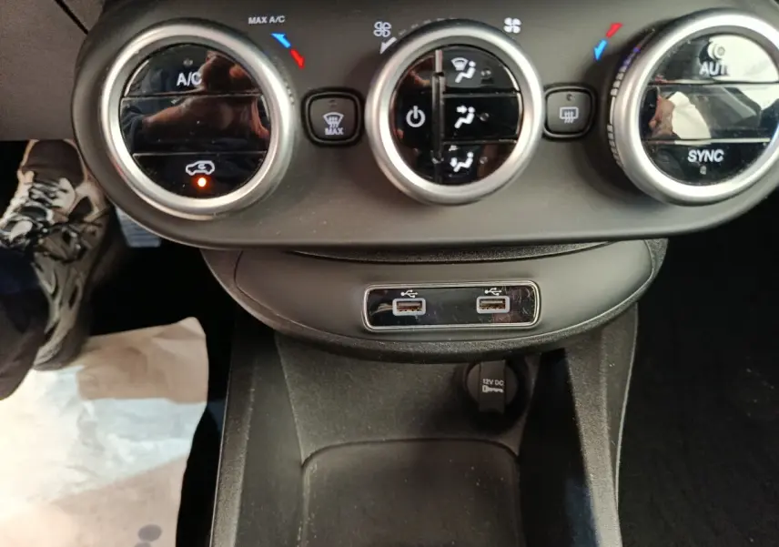 Vue rapprochée du tableau de bord central de la Fiat 500X blanc, montrant les commandes de climatisation et ports USB.