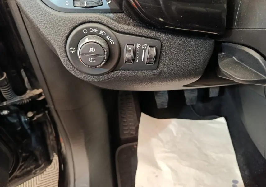 Gros plan sur les commandes d’éclairage et réglages du tableau de bord côté conducteur d’une Fiat 500X blanche.