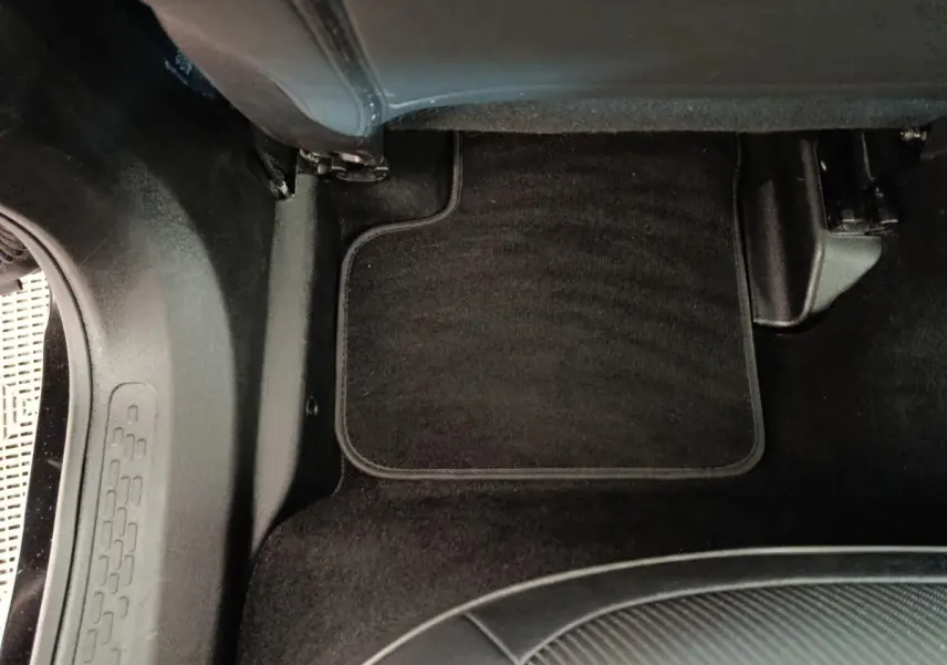 Détail du tapis de sol noir côté passager arrière du Fiat 500X blanc, intérieur sobre et propre.