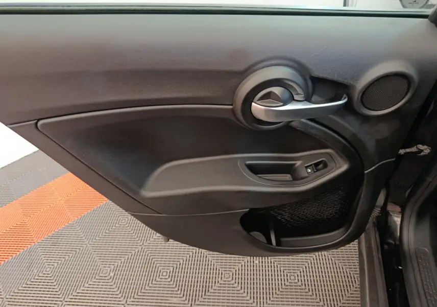 Gros plan sur la porte intérieure côté conducteur noire du Fiat 500X 2020 avec poignée argentée et commande de vitre électrique.