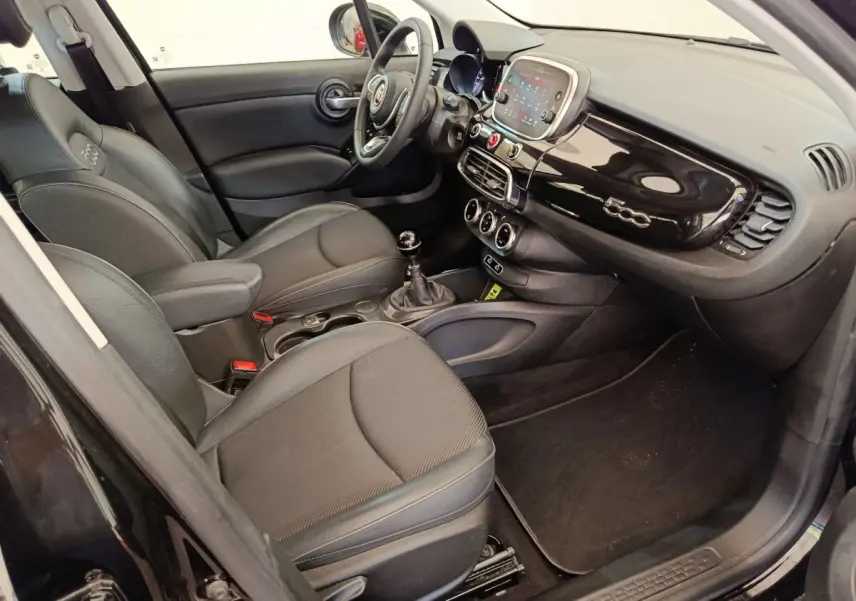 Intérieur noir de la FIAT 500X 2020 vu côté conducteur, tableau de bord brillant avec logo 500 et écran tactile central.