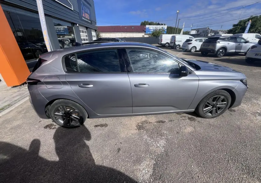 Profil droit d'une Peugeot 308 2024 gris Artense avec jantes alliage noires, garée en extérieur au soleil.