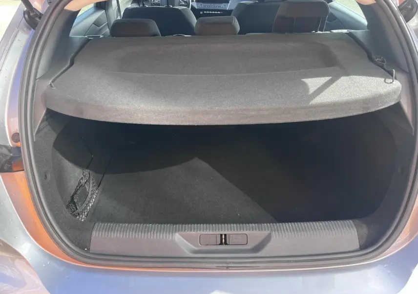 Coffre ouvert vu de l'arrière d'une Peugeot 308 gris Artense avec cache-bagages et banquette arrière visible.