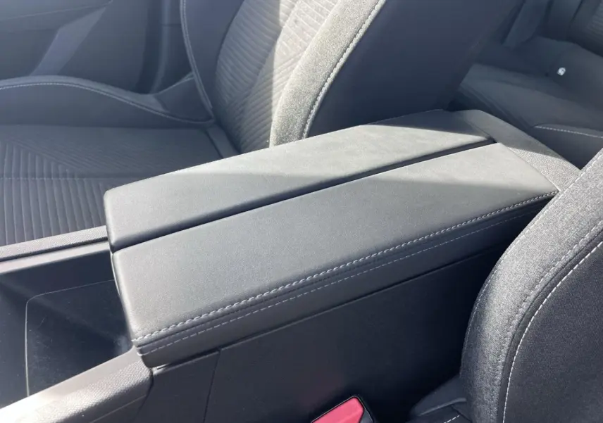 Accoudoir central avant gris avec rangement, sièges tissu noir à surpiqûres blanches dans Peugeot 308 2024.