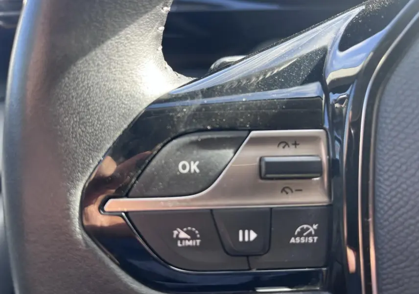 Gros plan sur les commandes du volant multifonction côté gauche d’une Peugeot 308 gris Artense 2024.