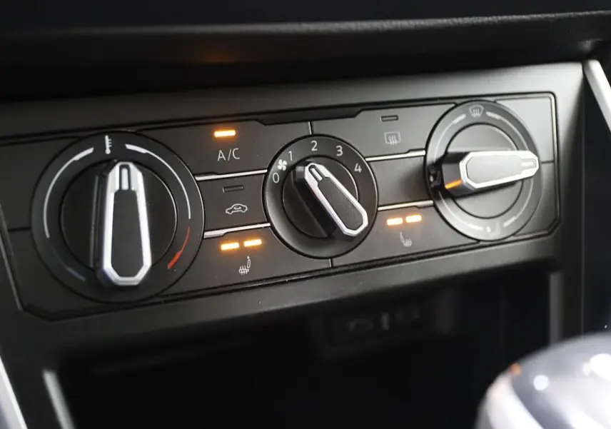 Gros plan sur les commandes de climatisation et sièges chauffants du Volkswagen Polo 2022 noir avec boîte automatique.