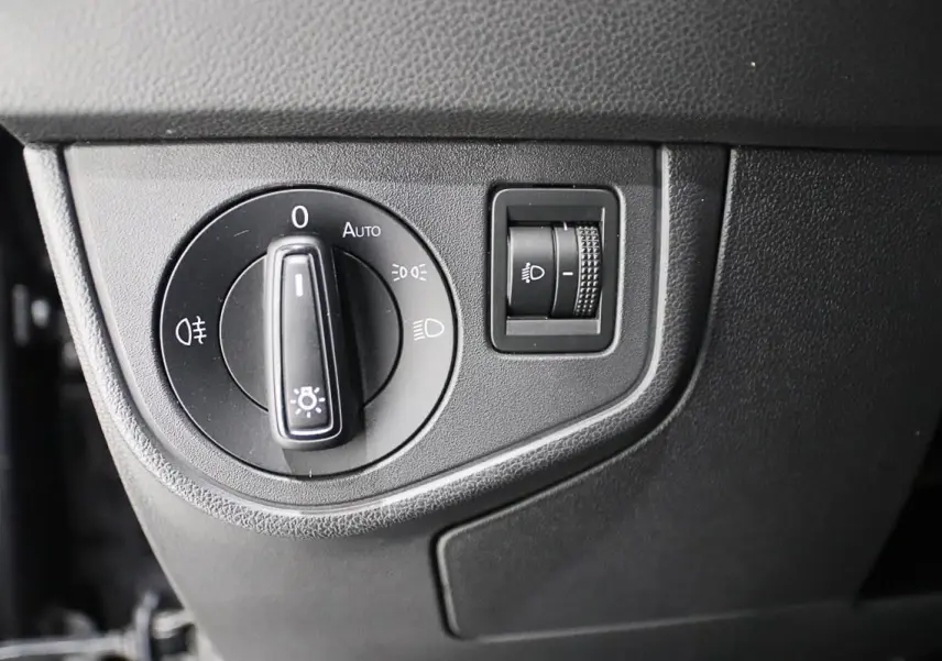 Gros plan sur le bouton de commande des phares et réglage d'intensité dans un Volkswagen Polo noir 2022.