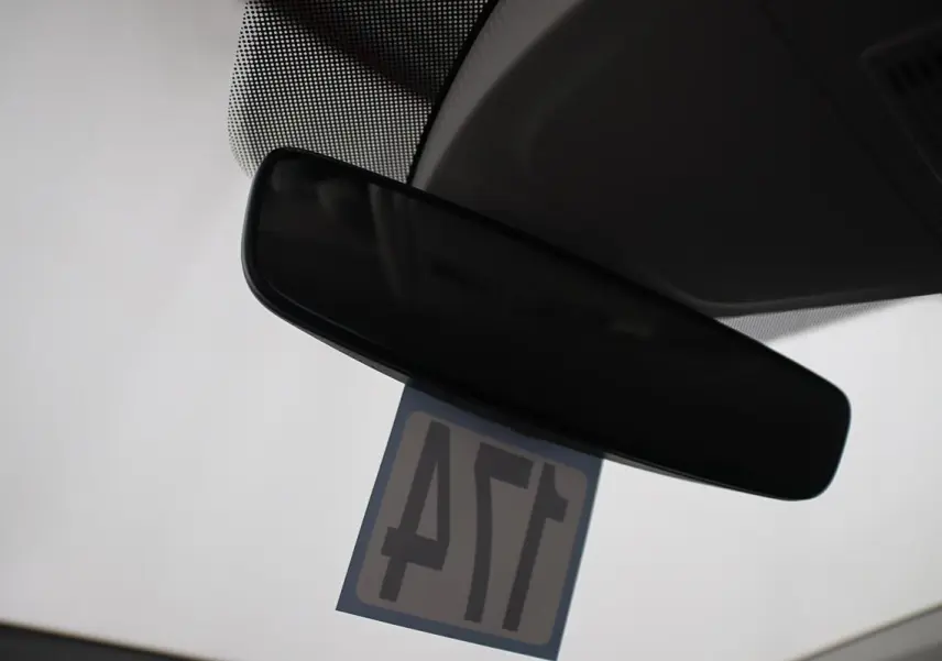 Rétroviseur intérieur noir d'une Volkswagen Polo 1.0 TSI 95 DSG vue depuis l'habitacle avec étiquette suspendue.