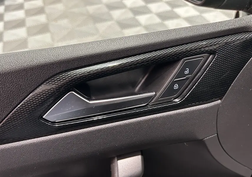 Gros plan sur la poignée intérieure côté gauche de la porte noire avec boutons de verrouillage déverrouillage.