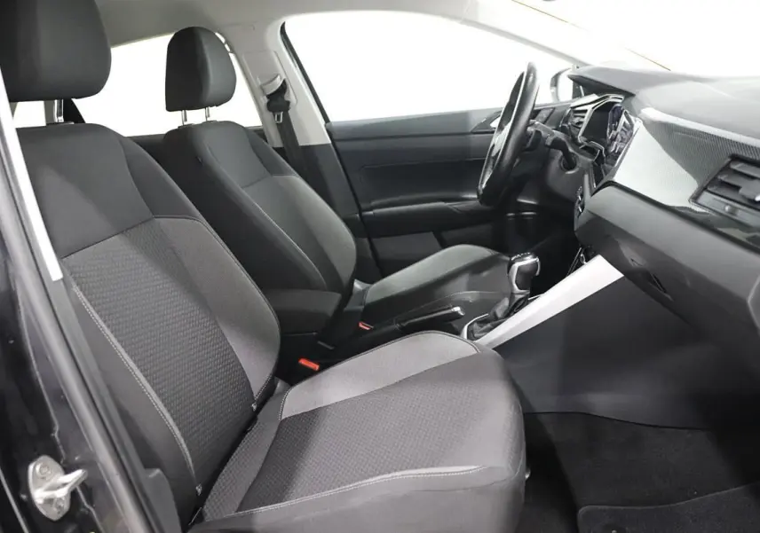 Vue intérieure côté conducteur de la Volkswagen Polo noire 2022 avec sièges tissu et tableau de bord moderne.