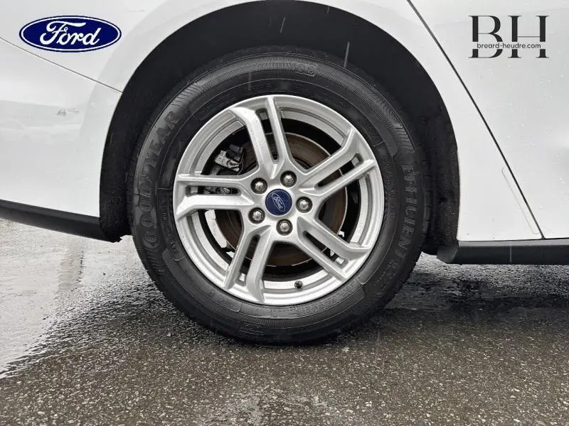 Gros plan sur la roue avant gauche de la Ford Focus SW blanche, avec jante alu et logo Ford au centre.